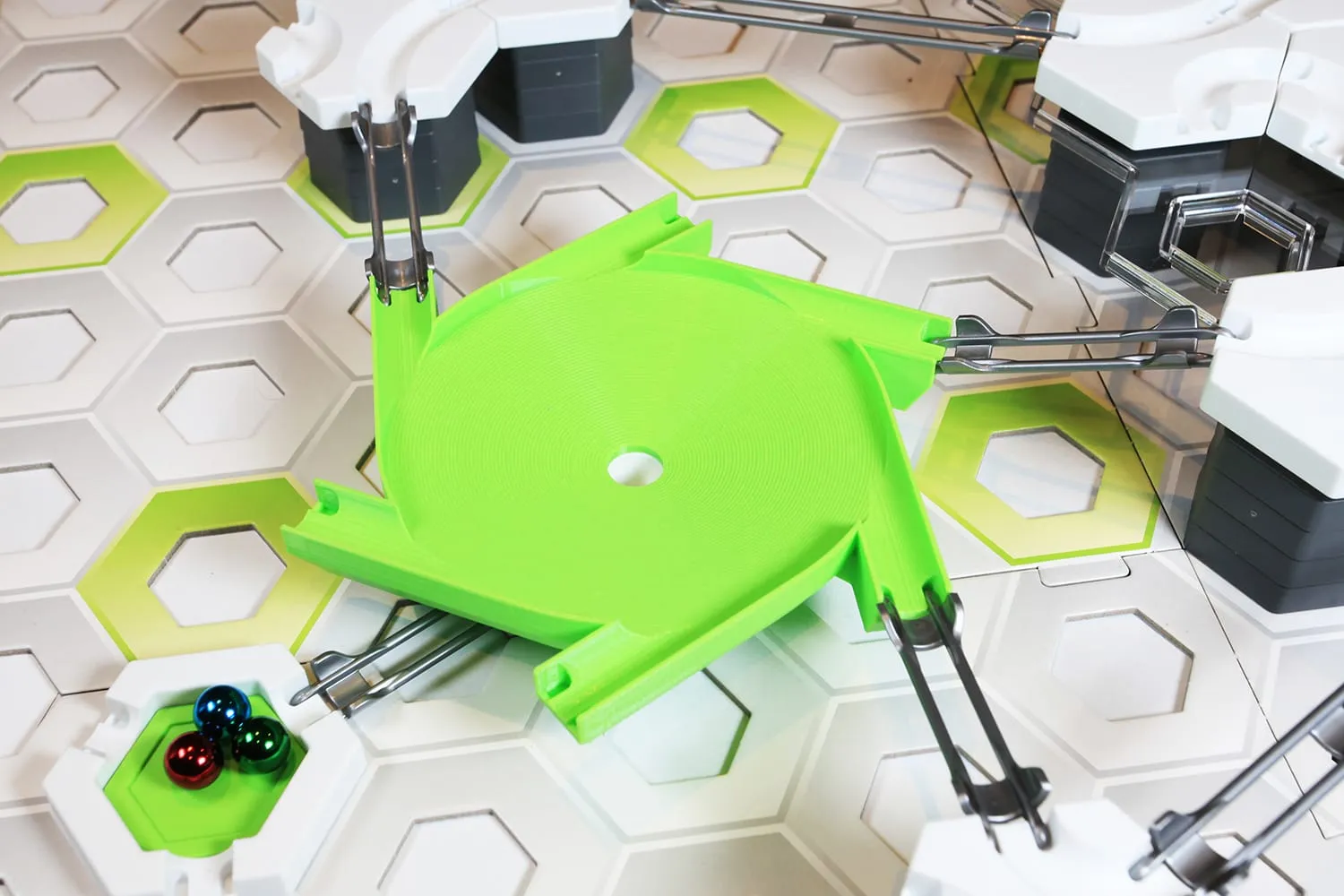 Méga toupie six entrées verte dans un circuit GraviTrax, trois billes dans une plaque verte en bas à gauche