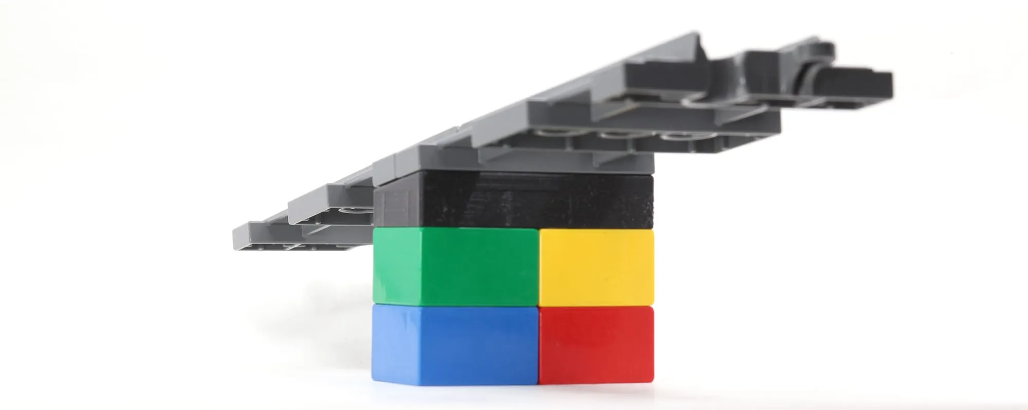 Rampe de rails DUPLO soutenue par une brique penchée sur des briques DUPLO colorées, vue de côté