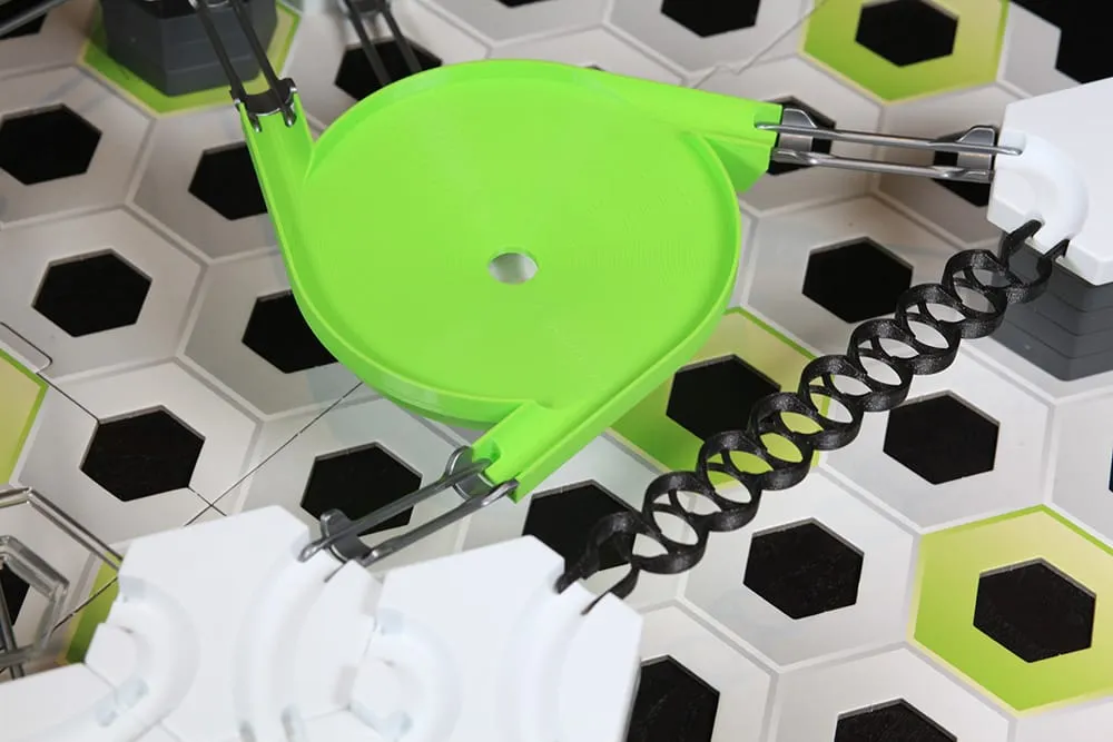 Méga toupie triple entrée verte dans un circuit GraviTrax, reliée à des rails et à un ressort noir