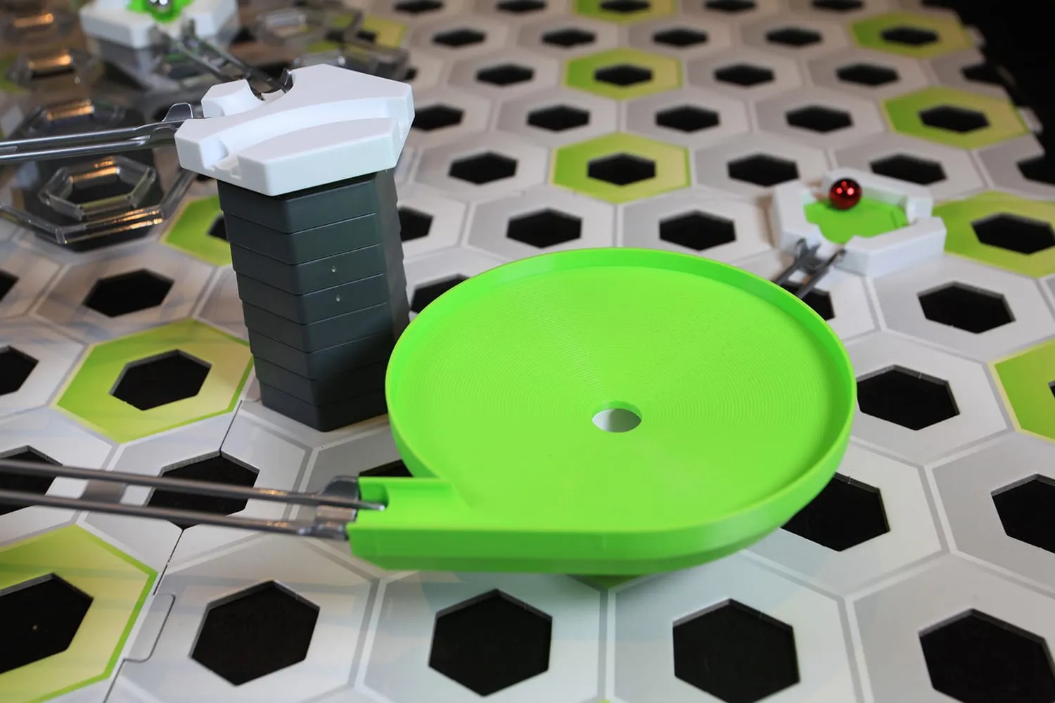 Méga toupie verte intégrée à un circuit GraviTrax, une bille rouge sur la piste