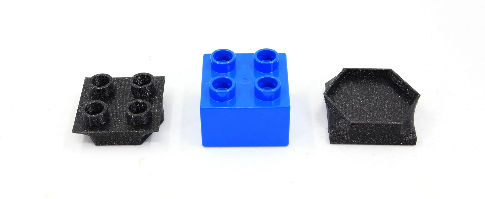 Adaptateurs haut et bas en PLA noir de part et d’autre d’une brique DUPLO bleue
