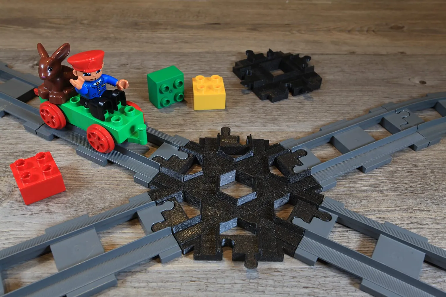 Train DUPLO vert et son conducteur approchant du croisement 6 voies noir