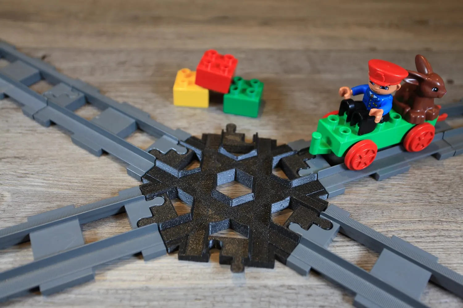 Croisement 6 voies noir sur des rails DUPLO croisés, un train vert à droite