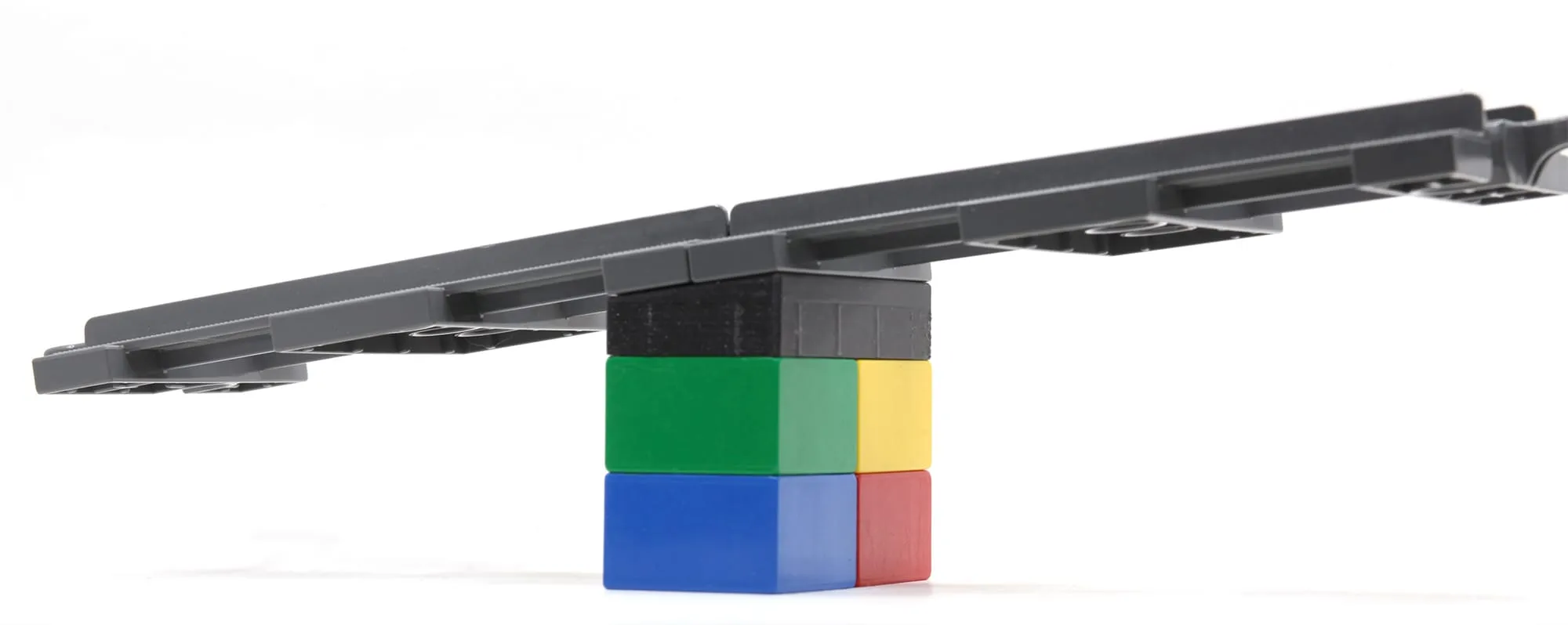 Rails DUPLO en pente sur une pile de briques colorées et une brique penchée noire, vue de côté
