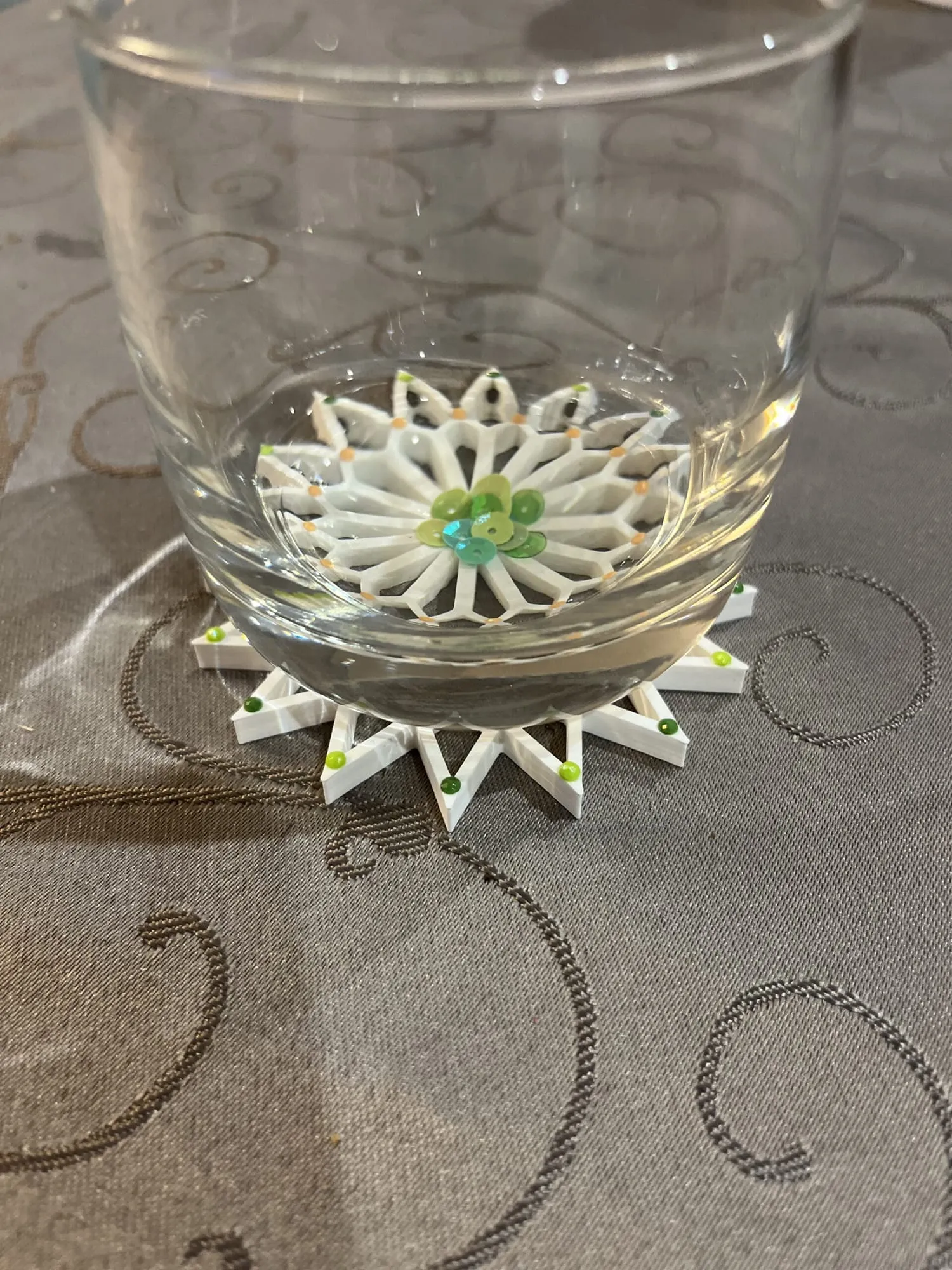 Étoile blanche décorée de petits points colorés et de paillettes, utilisée comme dessous de verre
