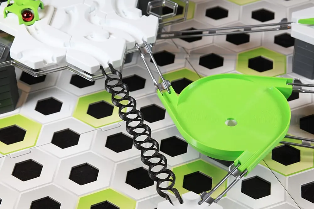 Rail zigzag noir passant près d’une méga toupie verte dans un circuit GraviTrax