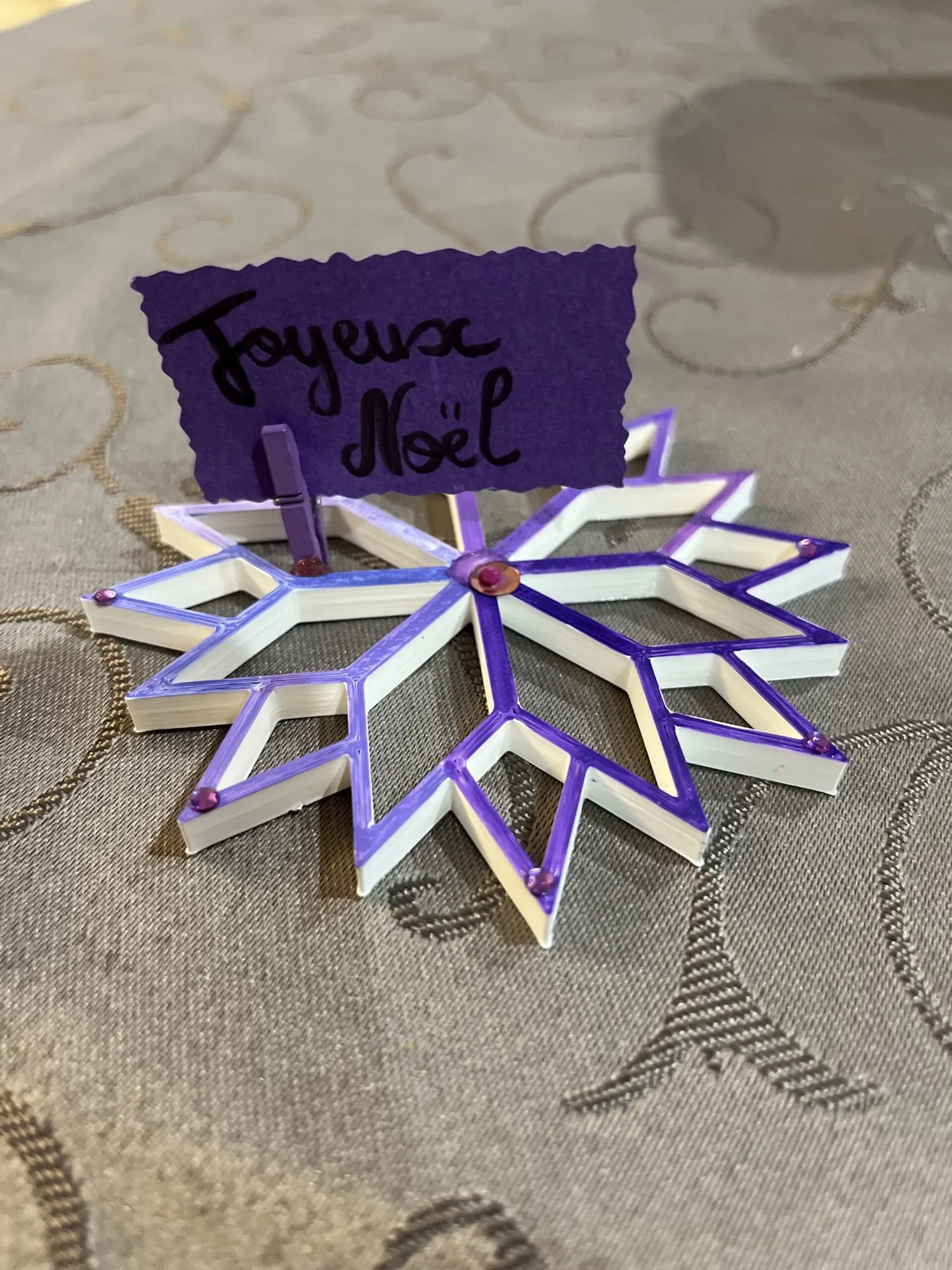 Marque-place « Joyeux Noël » : étoile blanche à bords violets portant une carte violette